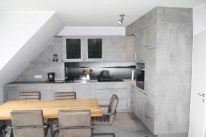 a kitchen with a wooden table and chairs at Seeblick 8 - Luxus direkt am Hafen von Norddeich in Norddeich