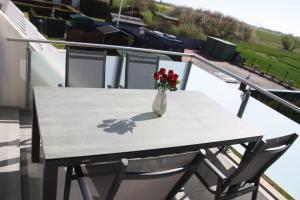 een tafel met een vaas met bloemen op een balkon bij Seeblick 8 - Luxus direkt am Hafen von Norddeich in Norddeich