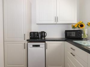 a kitchen with white cabinets and a microwave at Apartment at Morningside Hotel in Torquay