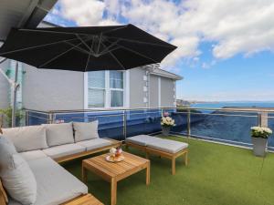 a patio with a couch and an umbrella at Apartment at Morningside Hotel in Torquay