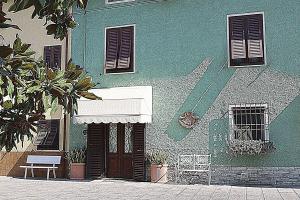 un edificio verde con una panchina davanti di Il Fiore all'Occhiello a Lucca