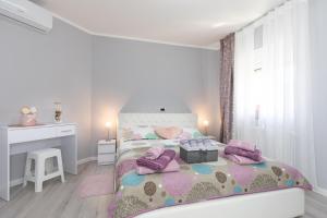 a white bedroom with a bed and a desk at Apartment Odore di Mare with beautiful garden in Krk