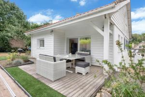 a patio with a table and chairs on a wooden deck at Magnifique maison avec piscine in La Baule