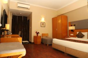 a hotel room with a bed and a desk at L'ELEGANT Hotel & Banquet in Ghaziabad