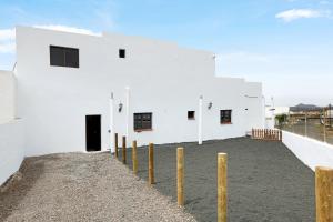 a white building with wooden poles in front of it at Casa Diego in Soo