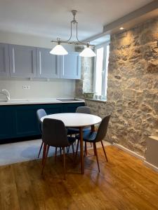eine Küche mit einem Tisch, Stühlen und einer Steinmauer in der Unterkunft Apartments Mia in Dubrovnik