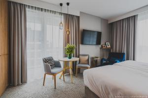华沙Royal Tulip Warsaw Centre的一间带床、桌椅的酒店房间