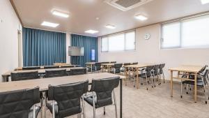 une salle de conférence avec des tables, des chaises et un écran dans l'établissement J View Hotel, à Seogwipo