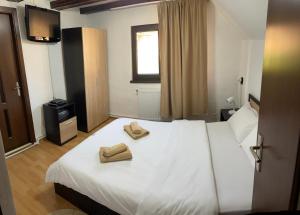 - une chambre avec un lit blanc et 2 serviettes dans l'établissement Vila Panoramic Pestera, à Peştera