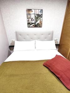 1 dormitorio con cama blanca y cabecero blanco en La Dorada, en Boiro
