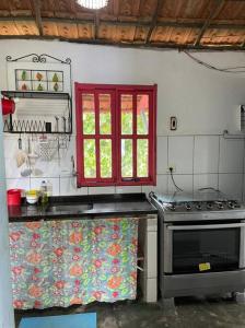 a kitchen with a stove and a red window at Casa das Falésias Cumuruxatiba in Cumuruxatiba