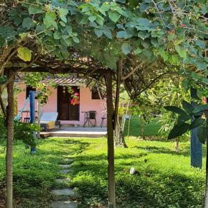 einen Garten mit einem Haus mit einem Spielplatz und Bäumen in der Unterkunft Casa das Falésias Cumuruxatiba in Cumuruxatiba