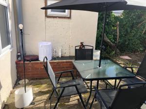 a patio with a table and chairs and an umbrella at Strand Beach View House in Gillingham