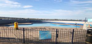 a swimming pool with a sign on a fence at Strand Beach View House in Gillingham