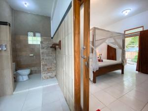 a bathroom with a shower and a toilet and a tub at Gili Spoy-Spoy in Gili Islands
