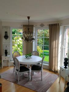een eetkamer met een tafel, stoelen en ramen bij Luana`s White Cottage in Surwold