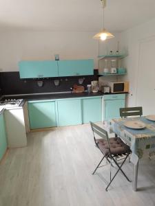 cocina con armarios azules, mesa y sillas en Maison Marilene, en Ajat