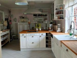 a kitchen with white cabinets and a sink at Luana`s White Cottage in Surwold