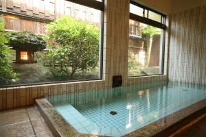 a swimming pool in a building with a large window at Kinosaki Onsen Kawaguchiya Honkan in Toyooka