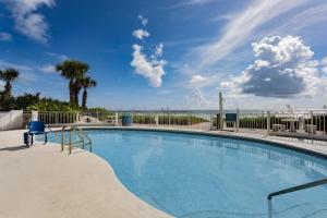 a swimming pool with the ocean in the background at Coconut Palms Beach Resort II a Ramada by Wyndham in New Smyrna Beach