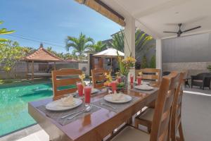 uma mesa de jantar e cadeiras com uma mesa e uma piscina em Villa Royal em Singaraja