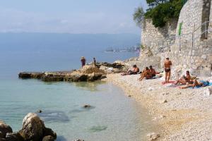 un grupo de personas sentadas en una playa cerca del agua en Rooms with WiFi Rijeka - 18278 en Rijeka