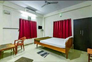 a bedroom with a bed and red curtains at Andaman Castle in Port Blair