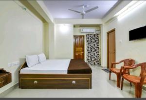 a bedroom with a bed and two chairs and a television at Andaman Castle in Port Blair