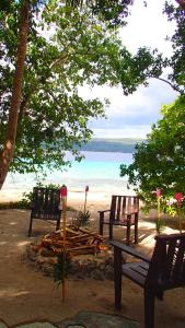 dois bancos e uma fogueira na praia em Tranquility Island Eco Dive Resort em Moso Island
