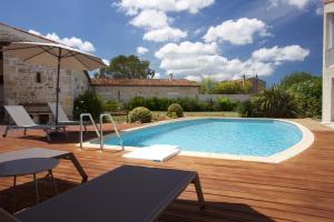 a swimming pool on a wooden deck next to a house at La Charentine in Échillais