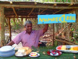 a man standing in front of a table with a sign at Tranquility Island Eco Dive Resort in Moso Island