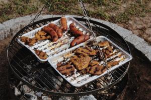 a grill with hot dogs and other food on it at Domek do wynajęcia - Siedlisko przy lesie in Rząśnik
