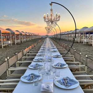 a long table with wine glasses on the beach at Danio beach house in Lido di Camaiore