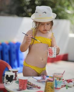 a little girl in a bikini and a hat holding a stick at CHARM BEACH HOTEL in Akyarlar