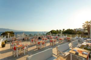 a patio with tables and chairs and the ocean at CHARM BEACH HOTEL in Akyarlar