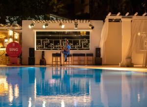 a man is sitting on a stool next to a swimming pool at CHARM BEACH HOTEL in Akyarlar
