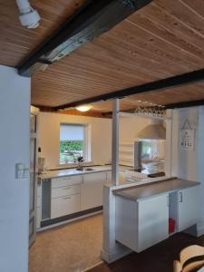 cocina con encimeras blancas y techo de madera en A cozy house to stay en Vandel