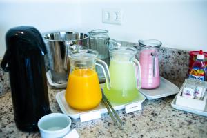 a counter with three glass containers of orange juice at Hotel Vila ÁguaMar in Itapoa