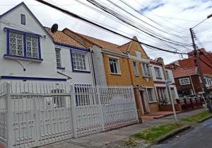 una cerca blanca frente a algunas casas en casa coral, en Bogotá