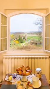 einen Tisch mit einem Teller Brot und einem Fenster in der Unterkunft Chambre d'Hôtes La Courbe in Lugan