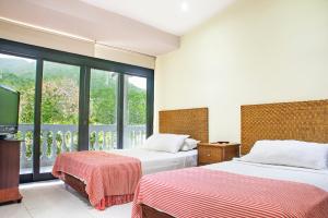 a bedroom with two beds and a large window at Santorini Villas del Mar Santa Marta in Santa Marta