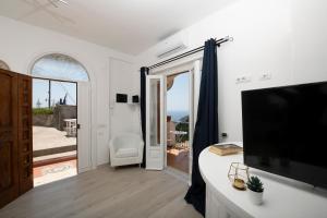 a living room with a television and a sliding glass door at Amalfi Venere house -balcony & seaview in Amalfi
