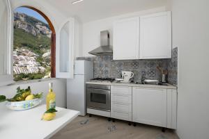 a white kitchen with white cabinets and a window at Amalfi Venere house -balcony & seaview in Amalfi