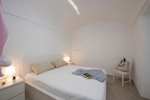 a white bedroom with a bed and a chair at Amalfi Venere house -balcony & seaview in Amalfi