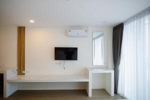 a living room with a tv on a white wall at Hotel Agnes in Buriram