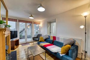 a living room with a blue couch and a tv at Guest Homes - The Basement On The Tything in Worcester