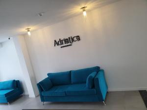 eine blaue Couch in einem Zimmer mit Schild an der Wand in der Unterkunft Adriatica Apartamentos in San Luis