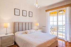 a white bedroom with a bed and a balcony at Casa Flor do Campo in Calheta
