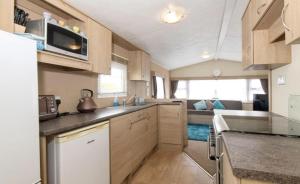 een keuken met houten kasten en een woonkamer bij Charming and peaceful 2-Bed Chalet in Hampshire in Warsash