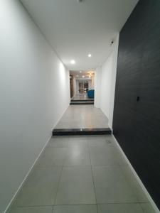 un pasillo vacío con paredes blancas y suelo de baldosa en Adriatica Apartamentos en San Luis